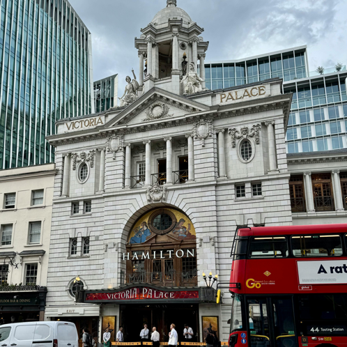 Das berühmte Victoria Palace Theatre in London mit einem vorbeifahrenden roten Doppeldeckerbus.