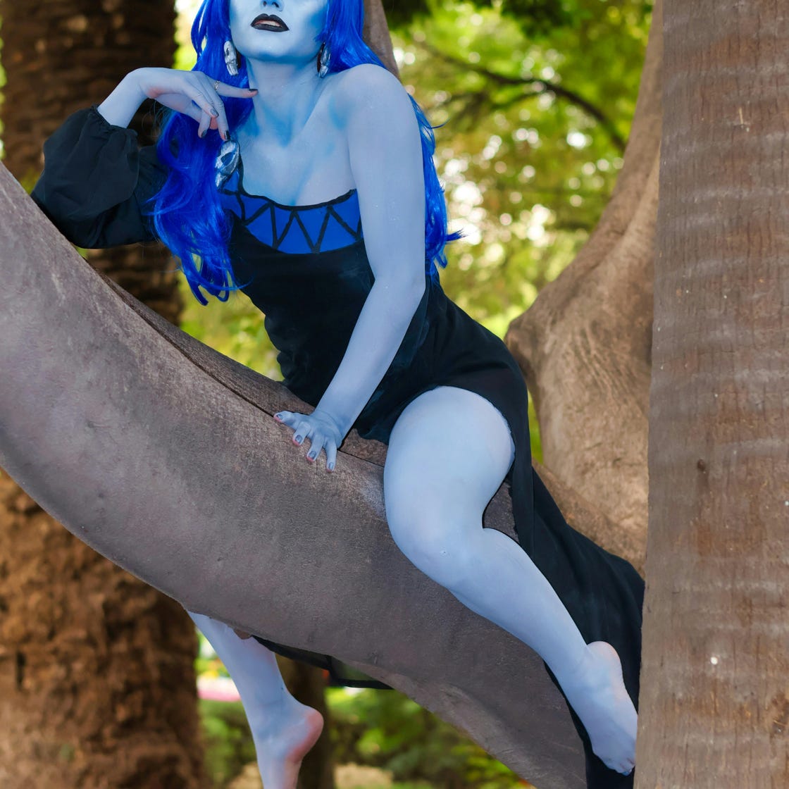 Blauhäutige Fantasyfigur mit leuchtender Perücke in einer Waldkulisse im Freien.